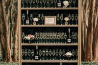 a unique champagne glass wall – a bookcase with greenery, glasses and bottles plus pastel bloom arrangements
