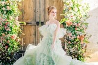 a unique pastel green tiered ruffle A-line wedding dress with a train and on spaghetti straps for more comfort is a unique idea