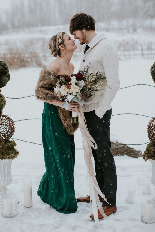 a winter bride wearing a green strapless wedding dress and a faux fur cove rup plus a boho updo looks amazing
