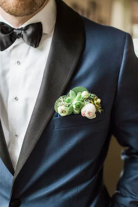 an elegant navy tux with black lapels and a pocket square for a fresh and modern touch, with blush and white blooms and succulents is wow