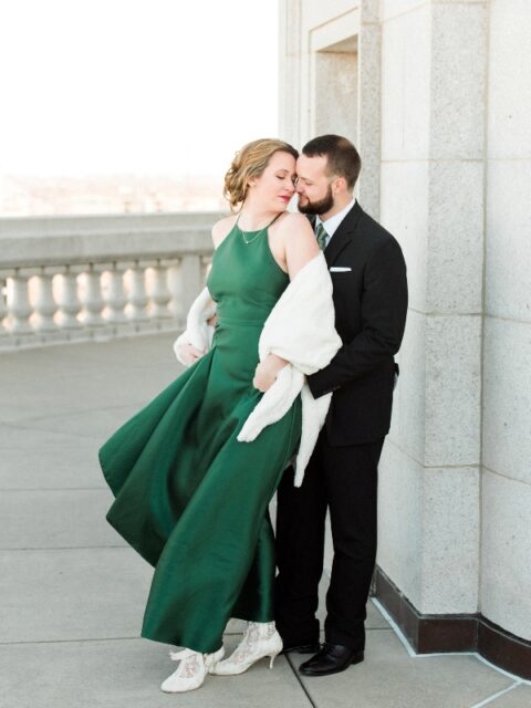 an emerald A line wedding dress with a halter neckline paired with vintage lace booties and a white faux fur wrap
