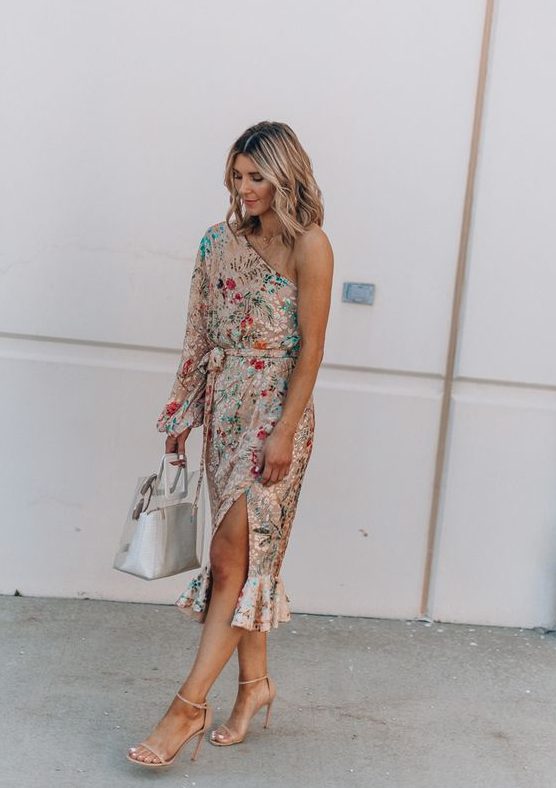 a bold floral one shoulder midi dress with a slit and a long sleeves plus statement earrings for a summer wedding