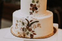 07 a stylish and trendy white buttercream wedding cake with pressed dried flowers and leaves composes two trends in one