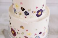 10 a delicate white buttercream wedding cake with a rough edge and a bit of mauve, purple and blue and yellow blooms pressed to form a pattern