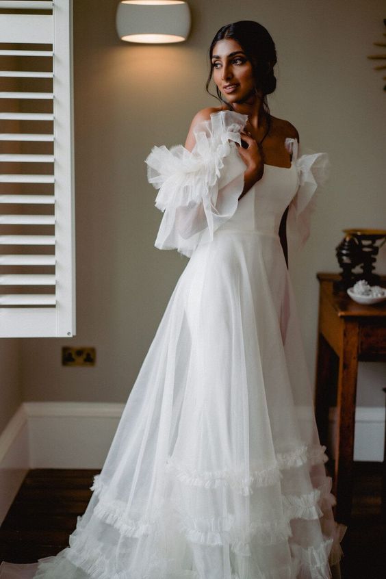 a beautiful off the shoulder A line wedding dress with ruffles on the sleeves and overskirt plus a train is wow