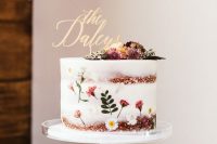 11 a gorgeous naked wedding cake with a bit of white and pink blooms and a leaf plus dried flowers on top and a calligraphy topper