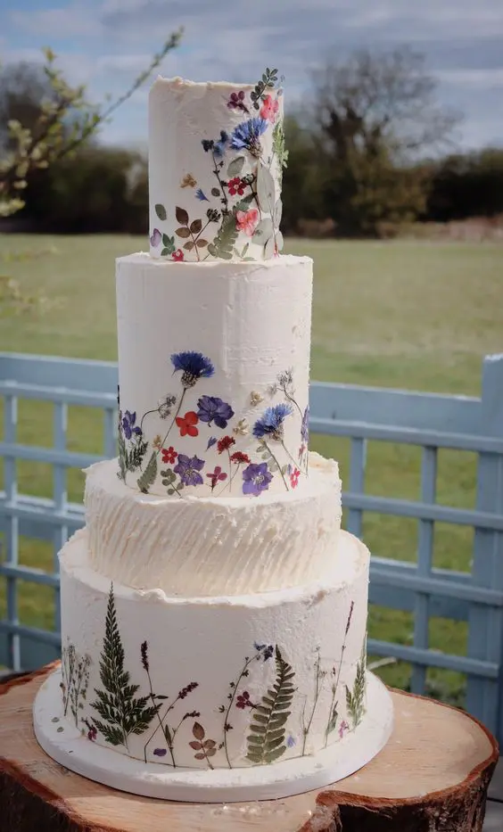 a multi tier white buttercream wedding cake with bold pressed flowers and leaves is a fabulous idea for a bright summer wedding