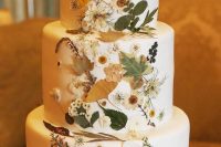14 a refined white buttercream wedding cake with neutral and white pressed blooms, greenery and herbs covering the front part of the cake only