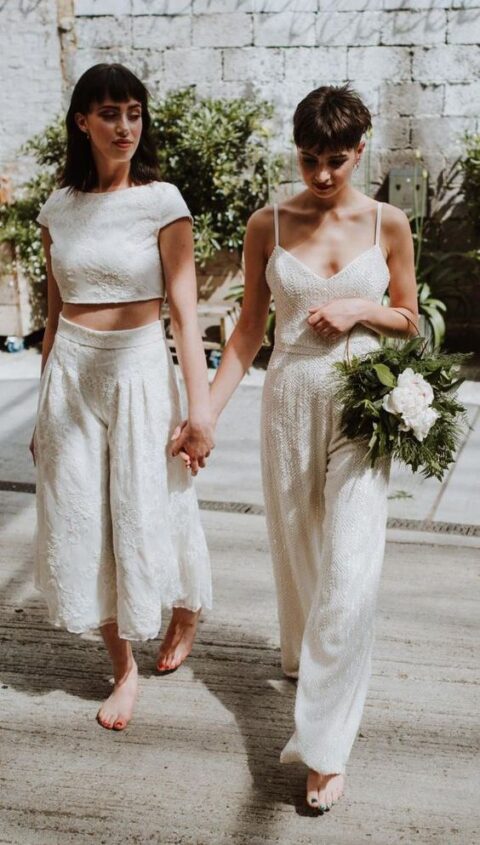 one bride wearing a lace separate with a crop top and culottes, and the other bride rocking an embbelished separate with a crop top and pants