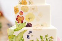 16 a white buttercream triangle wedding cake with painted leaves and pressed flowers forming a pattern on the cake