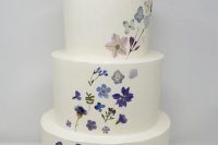 17 a white buttercream wedding cake with a delicate pattern o blue and purple blooms going up and a calligraphy topper