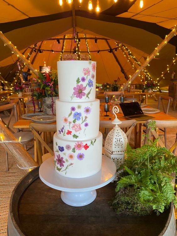 a white buttercream wedding cake with a pattern of pink, white and lilac pressed blooms is a lovely idea