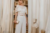 19 a chic bridal separate with a lace semi sheer crop top with a high neckline and short sleeves, plain high waisted pants and a shiny clutch