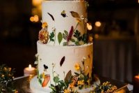20 a white buttercream wedding cake with bold blooms and greenery pressed to the cake is a decadent and refined idea for a fall wedding