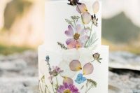 21 a white buttercream wedding cake with bright and pastel pressed blooms and greenery for a delicate spring wedding