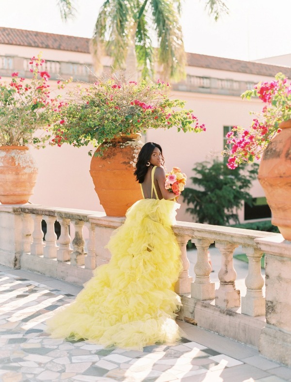 a bold yellow A line wedding dress with an open back and on spaghetti straps plus a tulle ruffle skirt with a train