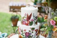 22 a white buttercream wedding cake with uneven edges and mustard, red and pink blooms and leaves pressed to it to form a pattern