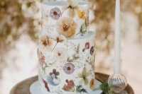 23 a beautiful white buttercream wedding cake with white, lilac, yellow pressed flowers and greenery looks incredibly chic