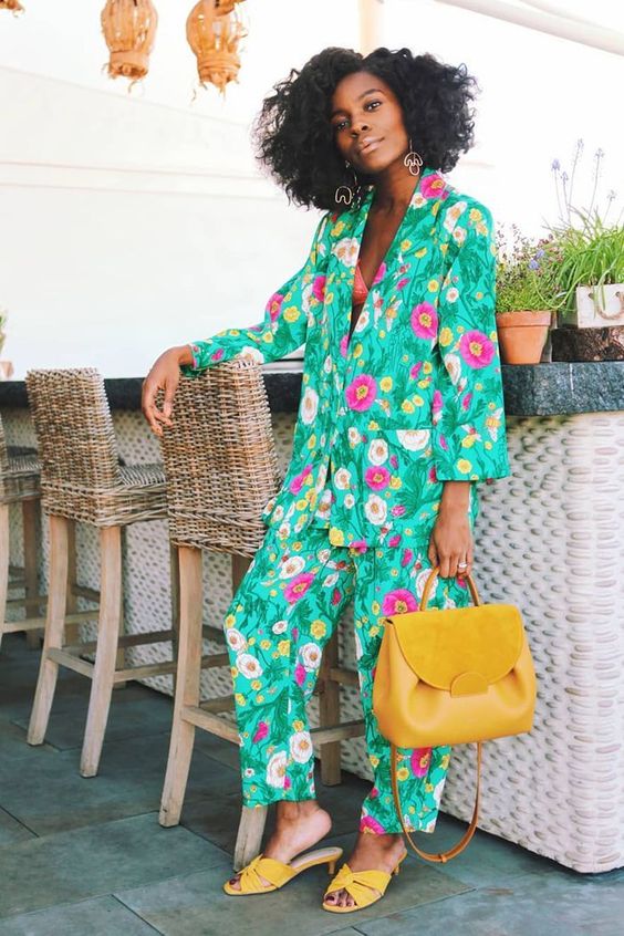 a super bright floral print pantsuit paired with catchy earrings and yellow mules and a bag for a summer garden wedding