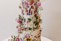 26 a fantastic wedding cake covered with white buttercream and with bright dried flowers and leaves pressed to it and attached for a voluminous look