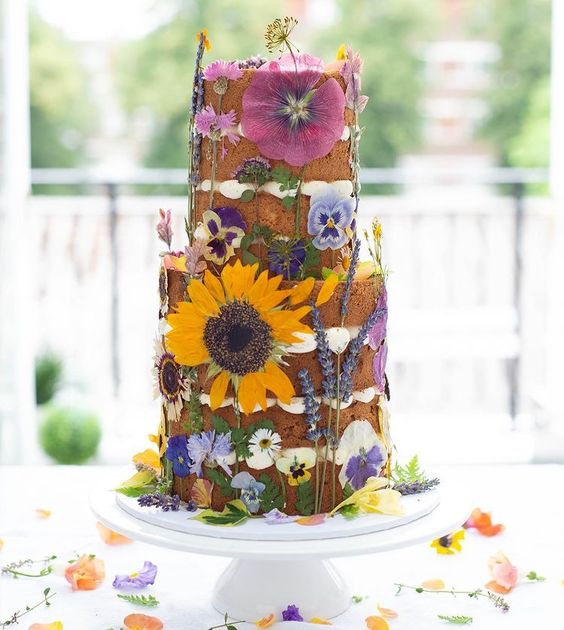 a naked wedding cake with pressed bold blooms and greenery is a gorgeous idea for a bright summer wedding