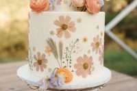 29 a lovely white buttercream wedding cake with wihte and blush pressed flowers and lilac and orange blooms on top for a spring celebration
