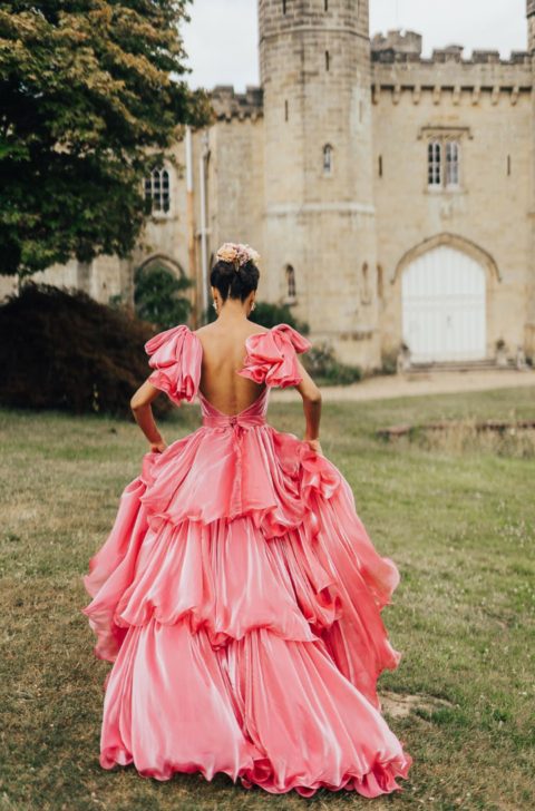 a gorgeous pink ruffle wedding dress with a tiered skirt and large bows on the shoulders plus a cutout back for a princess-style look