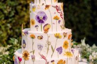 31 a pretty multi-tier white buttercream wedding cake with bright pressed flowers and leaves is a fun and cool idea for spring and summer weddings