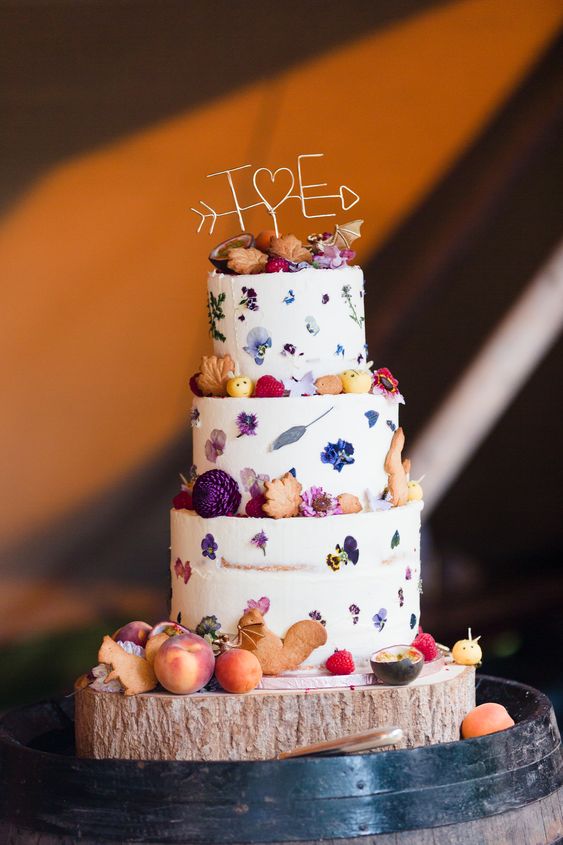 a semi naked wedding cake with pressed bright blooms and some dried flowers and leaf shaped cookies is amazing for a fall wedding