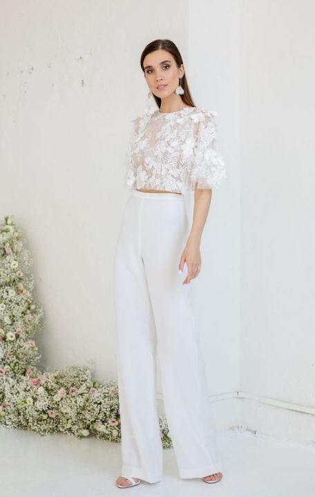 a super romantic and airy bridal look with a lace applique crop top with short sleeves, plain high waisted pants, white heels and floral earrings