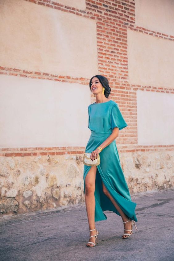 a lovely and chic blue maxi dress with a front slit, short sleeves, a high neckline, white shoes and a white clutch