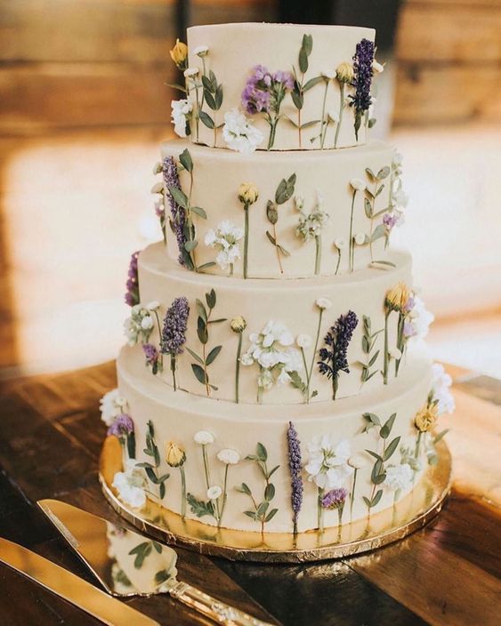 a tan wedding cake with pressed flowers and leaves looks very relaxed and boho like is a lovely idea for spring