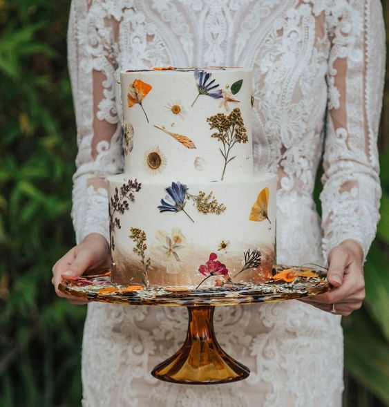 a white buttercream wedding cake with a copper touches and bright pressed flowers is amazing for a boho wedding