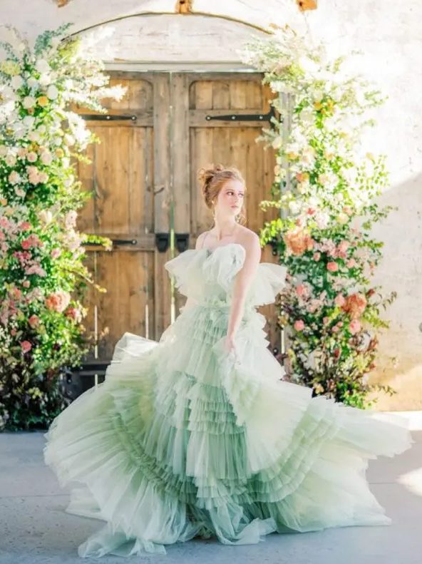 a unique pastel green tiered ruffle A line wedding dress with a train and on spaghetti straps for more comfort is a unique idea