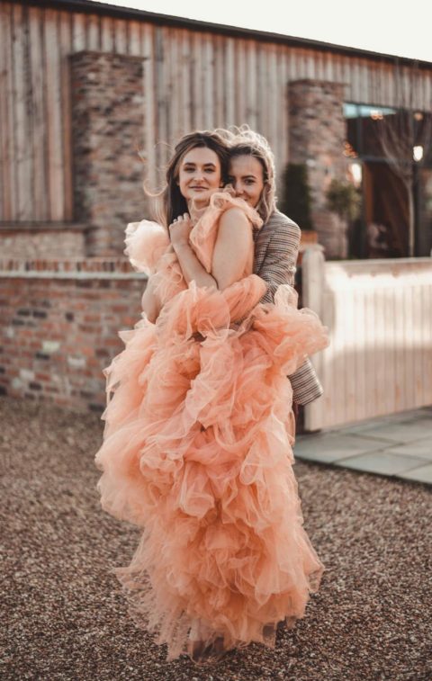 a whimsical peachy pink ruffle wedding dress with no sleeves will make a statement with both its color and design
