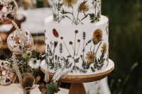 45 a white buttercream wedding cake with pressed dried blooms and leaves is amazing for a boho wedding