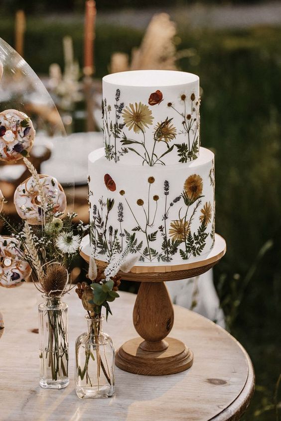 a white buttercream wedding cake with pressed dried blooms and leaves is amazing for a boho wedding