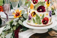 46 a white buttercream wedding cake with pressed super bold red, yellow and purple blooms and leaves is a gorgeous idea for a summer wedding