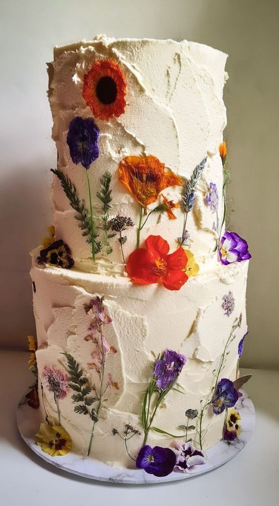 a white textural buttercream wedding cake with super bold blooms pressed to it looks fantastic and very eye-catchy