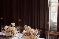 a refined wedding reception tablescape with pretty neutral florals, tall and thin candles and neutral porcelain is chic