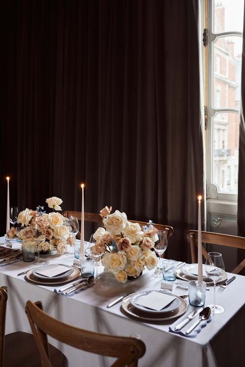 a refined wedding reception tablescape with pretty neutral florals, tall and thin candles and neutral porcelain is chic