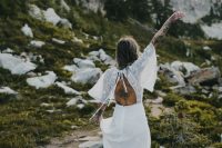 04 a boho mountain bride wearing a neutral wedding dress with lace appliques, a cutout back and wide sleeves is amazing