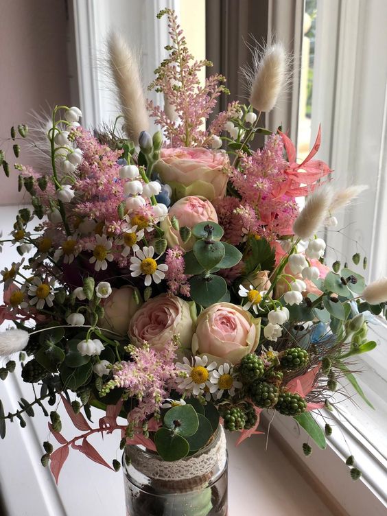 a bright summer wedding bouquet of blush blooms, wildflowers, astilbe, greenery, berries and bunny tails