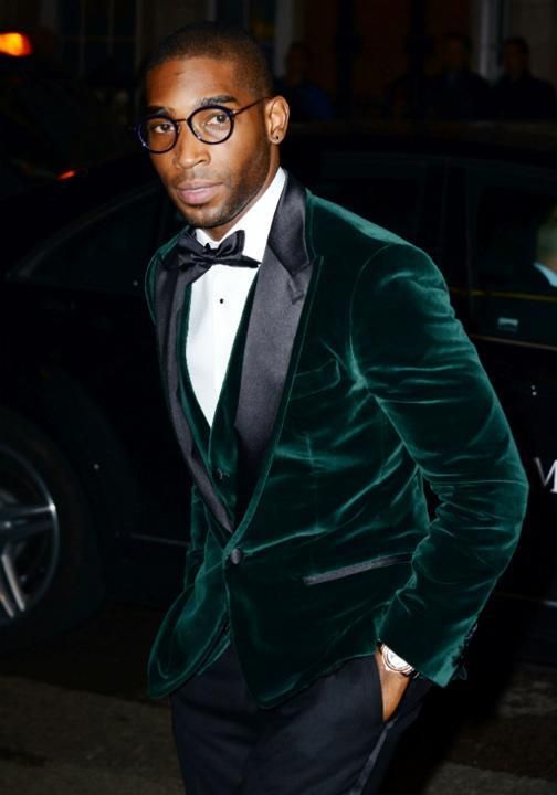 a chic black tie guest look with black trousers, a black bow tie, a white shirt with black buttons, an emerald velvet blazer and a matching waistcoat