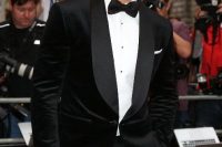 06 David Gandy wearing black trousers, a white shirt with black buttons, a black corduroy dinner jacket with matte lapels and a printed bow tie
