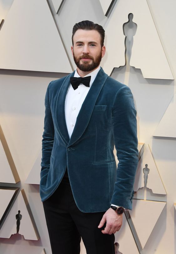Chris Evans wearing a white shirt, a black bow tie and pants, a slate blue velvet dinner jacket for a fresh take on black tie looks