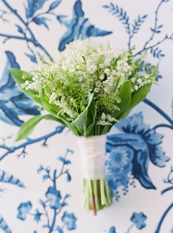 a lily of the valley wedding bouquet with greenery and with a white wrap is a very pretty idea for a spring wedding
