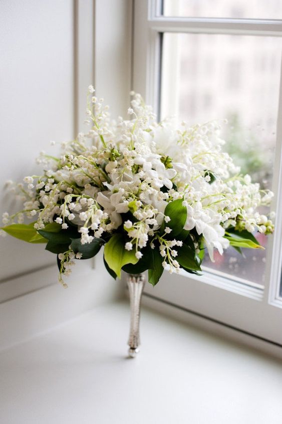 a lush wedding bouquet of lily of the vallet, white blooms and foliage and on a silver handle is a beautiful idea for a vintage wedding