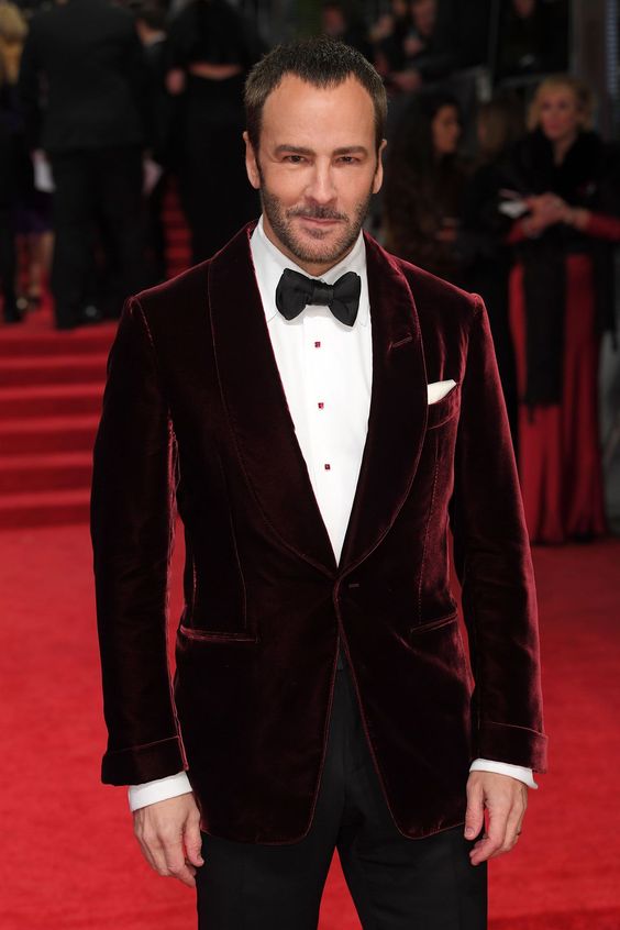 an elegant outfit with a white shirt with red buttons, black trousers, a burgundy velvet dinner jacket and a black bow tie