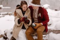 12 cool winter chalet wedding outfits with a tan faux fur coat, hiking boots, the groom wearing a burgundy blazer and a bolo tie for a boho feel